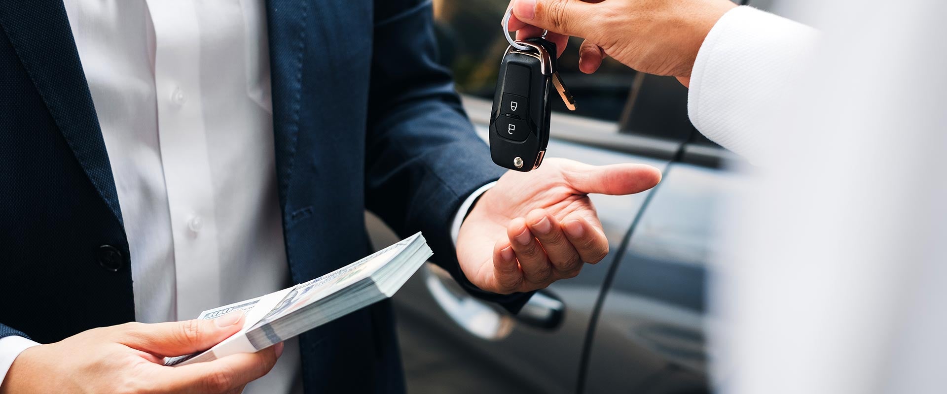 Customer receiving car keys from a salesperson beside a vehicle.