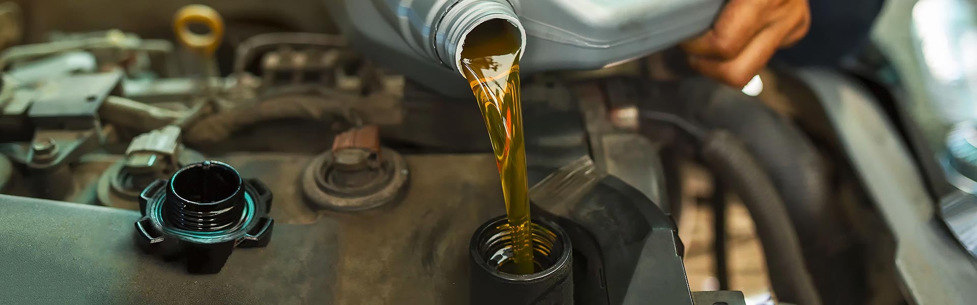 Engine oil being poured into a vehicle engine during an oil change service.